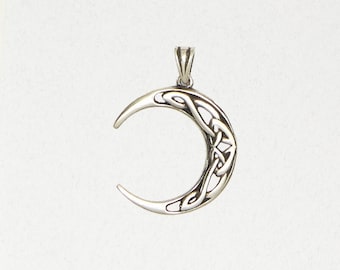 May include: A silver crescent moon pendant featuring Celtic knot patterns. The pendant has a loop for a chain. The moon's curved shape is smooth, and the knotwork is detailed. A piece of jewellery.