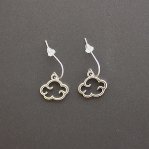 May include: A pair of silver-colored cloud-shaped earrings. Each earring features a cloud charm suspended from a curved wire and a post with a clear backing. The earrings are displayed against a dark gray background.