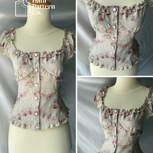 May include: A beige corset-style top featuring a pink floral pattern, a square neckline, short ruffled sleeves, and a front button closure. The garment includes ruffled trim along the neckline, sleeves, and hem, with the text Hani Pattern Co.