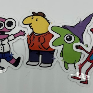 May include: A collection of four cartoon character stickers. The characters are in various colors, including pink, yellow, and green, and are wearing different outfits. The stickers have a glossy finish and are on a white background.