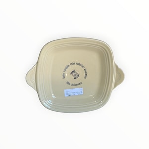 May include: A square, cream-colored ceramic baking dish with two side handles and concentric ring detailing. The center features a circular logo with the text Homer Laughlin China Collectors Association and 20th Anniversary.