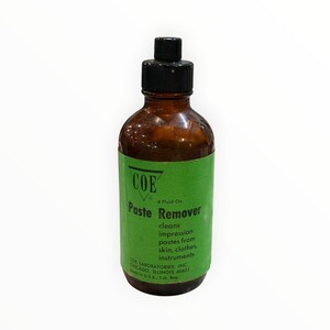 May include: A brown glass bottle with a black screw-top cap and a green label. The label reads COE Paste Remover, 4 Fluid Oz., cleans impression pastes from skin, clothes, instruments, COE Laboratories, Inc. Chicago, Illinois 60621, Made in U.S.A.