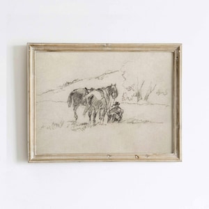 May include: A framed pencil sketch depicts a pastoral scene with two horses and a person. The artwork, in shades of gray, features a person seated near the horses in a field, with a distant hill and trees. The frame is a light, natural wood.