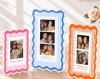 May include: Three rectangular acrylic photo frames with wavy scalloped edges in pink, blue, and orange stripes. Each frame displays a vertical photo strip with printed text at the bottom reading Love you Bestie, Sister est. 2024, and Will you be my maid of honor.