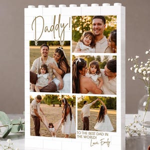 May include: A white block-style photo display with the word "Daddy!" in gold script. The display features family photos and the text "TO THE BEST DAD IN THE WORLD! Love, Emily."