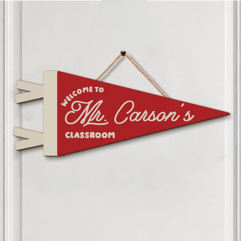 May include: A red triangular pennant banner with a cream-colored header and two side tabs. The text reads "WELCOME TO Mr. Carson's CLASSROOM" in cream-colored lettering. A tan rope is attached to the top for hanging the decorative wall sign.