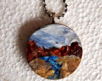 Red rock river valley is an original,  OOAK, handpainted wooden pendant/necklace.  Beautiful red rock hills with a stream. Wearable art.