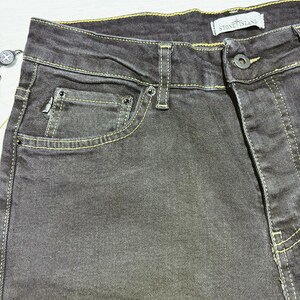 May include: Close-up of dark gray denim jeans with yellow stitching. The jeans have a classic five-pocket design, a button closure, and a small logo tag that reads "STONE ISLAND".