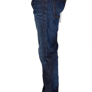 May include: Dark wash denim jeans with a classic five-pocket design. The jeans have a straight leg fit and are worn with white sneakers. The denim has a slight fade and subtle texture.