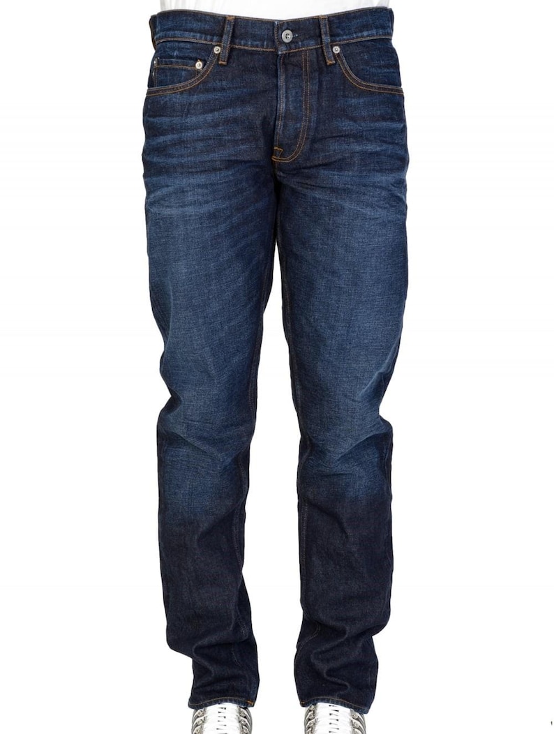 May include: Dark wash denim jeans with a classic five-pocket design. The jeans have a straight leg fit and feature copper-colored stitching and rivets. The denim has a slight fade, giving it a worn-in look. The jeans are a versatile wardrobe staple.