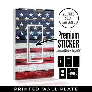 May include: Printed wall plate featuring a design of the American flag. The plate has a white border and a cutout for a light switch. The design includes red and white stripes and white stars on a blue background. The text "Premium Sticker" is also visible.