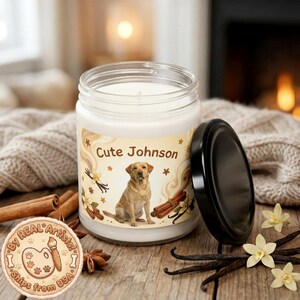 Puede incluir: Una vela en tarro de cristal con tapa negra, con una etiqueta con el texto "Cute Johnson" y una ilustración de un labrador amarillo. La etiqueta también incluye imágenes de palitos de canela, vainas de vainilla y estrellas. La vela está rodeada de palitos de canela, vainas de vainilla y flores.