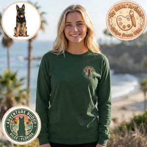 Puede incluir: Una camiseta de manga larga verde oscuro con un gráfico circular que dice "Adventure Buddy Kilee Florida" con la silueta de un perro pastor alemán. La camiseta la lleva una persona con cabello rubio. Un perro pastor alemán está en la esquina superior izquierda.