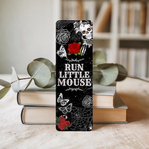 May include: Black bookmark with a gothic design featuring a skull, roses, butterflies, and a spiderweb. The text "RUN LITTLE MOUSE" is displayed in white. A red rose is in the center of the bookmark.