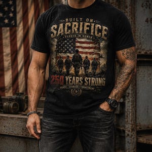 Puede incluir: Una camiseta negra de manga corta con un estampado gr&aacute;fico que incluye el texto BUILT ON SACRIFICE, FORGED IN HONOR, 250 YEARS STRONG, HONOR, COURAGE, COMMITMENT y una ilustraci&oacute;n de cinco soldados frente a una bandera estadounidense.