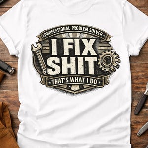 Può includere: T-shirt bianca con una grafica che recita "I FIX SHIT THAT'S WHAT I DO". Il design include una chiave inglese, un ingranaggio e uno striscione con la scritta "Professional Problem Solver."