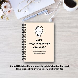 Puede incluir: Una mini guía con espiral titulada "ADHD 'LOW-ENERGY DAY' MINI GUIDE" con un gráfico de cerebro y bombilla. La guía está sobre una superficie clara con un bolígrafo, gafas y auriculares cerca. El texto en la parte inferior dice: "AN ADHD-friendly low-energy mini guide..."