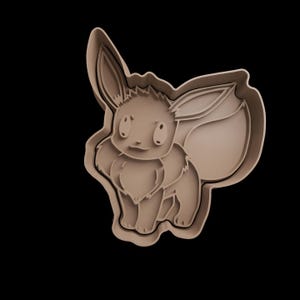 May include: A tan-coloured Eevee cookie cutter. The cutter is in the shape of the popular Pokémon character, with detailed features including large ears, a fluffy chest, and a bushy tail. The cutter is made of plastic and is designed for cutting cookie dough.