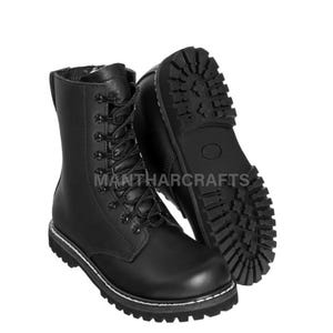 May include: Black leather combat boots with a lace-up design and a thick, rugged sole. The boots have a mid-calf height and a white stitched detail around the sole. The text "MANTHARCRAFTS" is visible on the side of the boot.