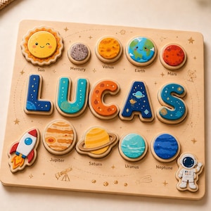 Può includere: Una tavola puzzle in legno con il nome LUCAS in grandi lettere a tema spaziale. La tavola include pezzi in legno rimovibili a forma di Sole, pianeti da Mercurio a Nettuno, un razzo e un astronauta, tutti con disegni colorati.