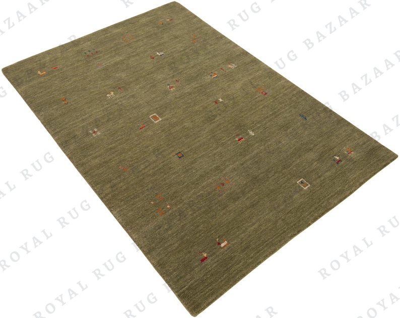 May include: A rectangular olive green rug with a textured surface. The rug features small, scattered geometric shapes in various colors, including red, white, and brown. The rug is a floor covering.