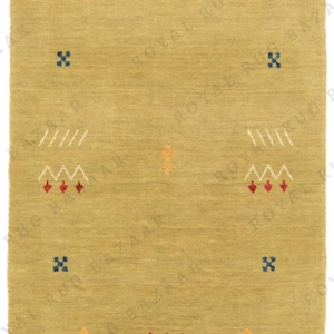 May include: A rectangular, olive-green rug with a textured surface. The rug features repeating patterns of white zigzags, red and blue geometric shapes, and camel silhouettes in orange. The rug's design is symmetrical.