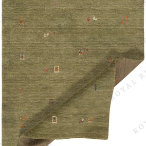 May include: Olive green area rug with a geometric pattern of small, colorful shapes. The rug has a textured surface and a folded corner revealing a brown underside. The design includes squares, rectangles, and abstract figures in orange, blue, and white.