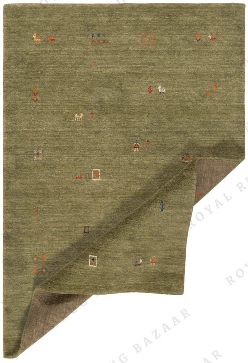 May include: Olive green area rug with a geometric pattern of small, colorful shapes. The rug has a textured surface and a folded corner revealing a brown underside. The design includes squares, rectangles, and abstract figures in orange, blue, and white.
