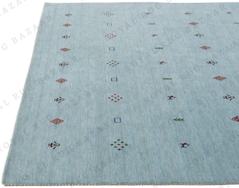 May include: A light blue rug with a repeating pattern of geometric shapes in red, green, and blue. The rug has a soft texture and a simple, modern design, suitable for a living room or bedroom.