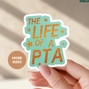 May include: A sticker with the text "THE LIFE OF A PTA" in orange glitter lettering on a teal background. The sticker is held by a hand. The words "MORE SIZES" are in a brown circle.