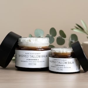 May include: Two glass jars of lavender-scented whipped tallow balm with black lids. The jars have white labels with black text that reads "Bare Soap & Body Whipped Tallow Balm" and "Handcrafted using grass-fed tallow". The larger jar contains 100ml/60g.