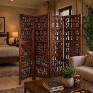 May include: A four-panel wooden room divider with intricate geometric cutouts. The divider is a warm brown color and stands in front of a bed and a sofa. The room is decorated in neutral tones with a natural aesthetic.