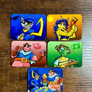 May include: Set of five rectangular metal magnets featuring cartoon characters in vibrant colors. Each magnet showcases a different character with unique designs and poses, set against colorful backgrounds. The magnets are arranged on a wooden surface.