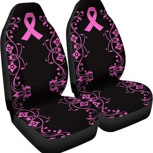 Puede incluir: Dos fundas de asiento de coche negras con un lazo rosa y un diseño floral. Cada funda tiene un lazo rosa en la parte superior. Las enredaderas y flores rosas adornan las fundas.