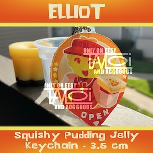 May include: A circular acrylic keychain featuring a yellow cartoon character wearing a red hat and shirt, holding a slice of pizza. The design includes the text "ROBLOX" and "OPEN" with a star border. The keychain is 3.5 cm in size.