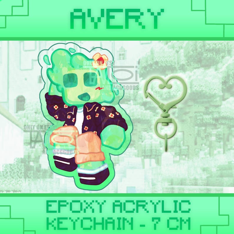 K&ouml;nnte beinhalten: Avery Epoxy-Acryl-Schl&uuml;sselanh&auml;nger mit einer gr&uuml;nen Cartoon-Figur mit Blumenjacke und herzf&ouml;rmigem Verschluss. Der Schl&uuml;sselanh&auml;nger ist ca. 7 cm lang. Das Wort "AVERY" steht oben im Bild.