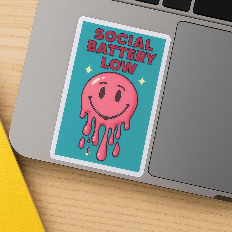 K&ouml;nnte beinhalten: Ein rechteckiger Aufkleber mit dem Text "SOCIAL BATTERY LOW" in roten Buchstaben. Der Aufkleber zeigt ein rosa, schmelzendes Smiley-Gesicht auf t&uuml;rkisem Hintergrund, mit gelben Sternakzenten.