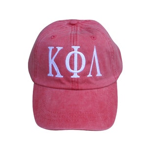 May include: A red baseball cap with white embroidered letters that spell "KΦΛ".