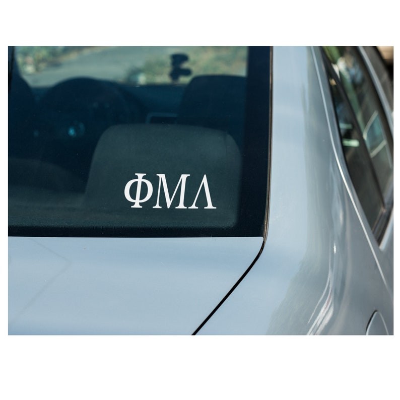 May include: A white car with a white vinyl sticker on the back window that says "&Phi;&Mu;&Lambda;".