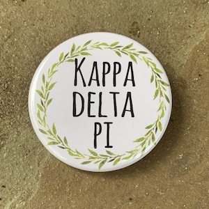 May include: White button with a green leafy wreath around the text "Kappa Delta Pi".