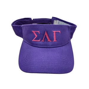 May include: Purple visor with a pink embroidered "ΣΛΓ" logo.