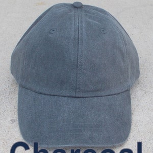 May include: A charcoal gray baseball cap with a curved brim. The cap is made of a durable fabric and features a button on top. The word "Charcoal" is printed in a dark blue font at the bottom of the image.