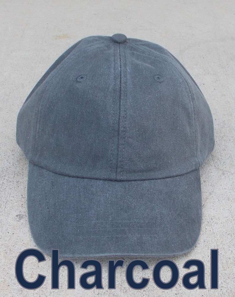 May include: A charcoal gray baseball cap with a curved brim. The cap is made of a durable fabric and features a button on top. The word "Charcoal" is printed in a dark blue font at the bottom of the image.