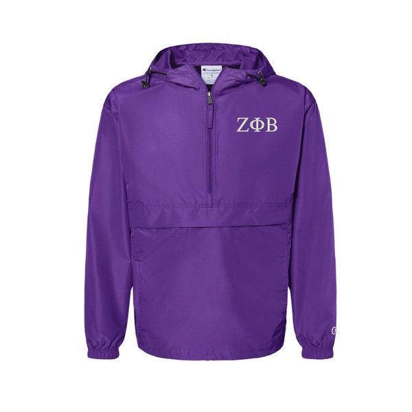 Op de afbeelding: Paarse Champion pull-over jas met een witte rits en een wit geborduurde "ZΦB" op de voorkant.