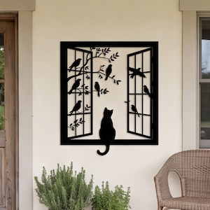 Puede incluir: Una pieza de arte mural de metal negro con un diseño de marco de ventana cuadrado. La silueta muestra a un gato sentado en el alféizar mirando a varios pájaros posados en ramas que se extienden desde el lado del marco de la ventana.