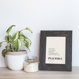 May include: A framed print with a black wood frame and a white background. The print features a black and white text quote from Psalm 86:5, "You, Lord, are forgiving and good, abounding in love to all who call to you."