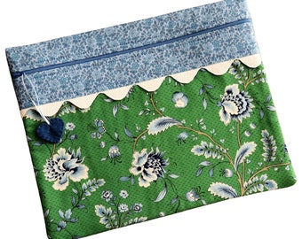 May include: A green zippered pouch with a blue and white floral pattern. The pouch has a white scalloped trim and a blue heart charm.