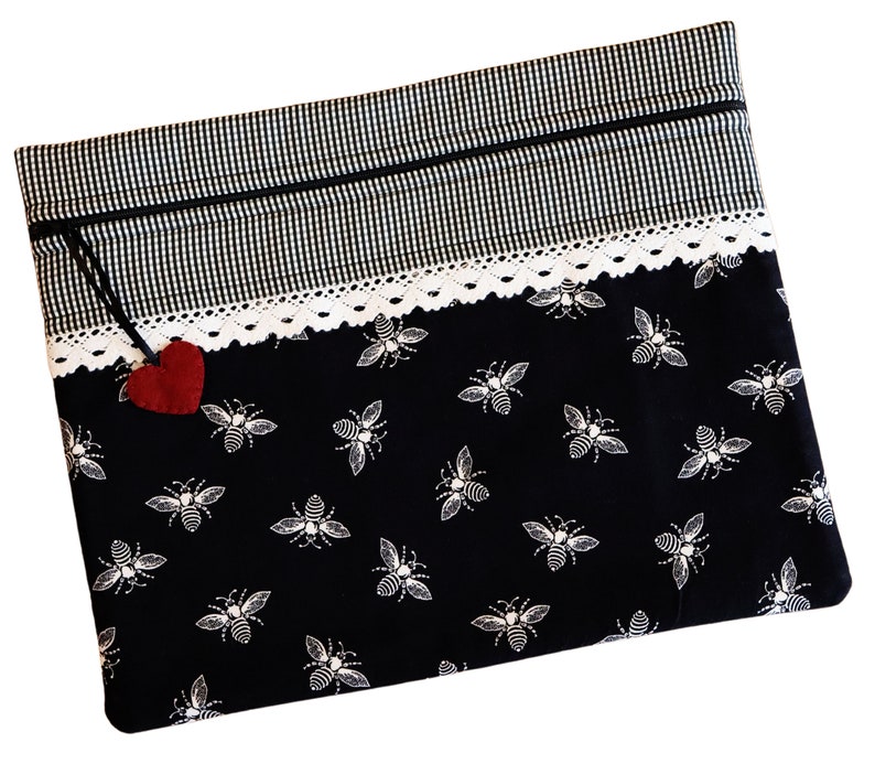 May include: Black zippered pouch with a white lace trim and a black and white gingham pattern on the top. The pouch has a red felt heart attached to the zipper pull and a black and white bee pattern on the bottom.
