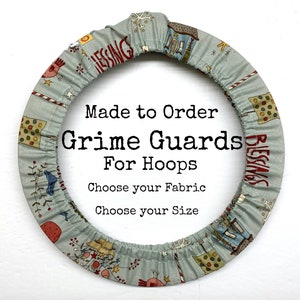 May include: A light blue fabric hoop cover with a red and white pattern. The cover has the text "Blessings" and "Made to Order Grime Guards for Hoops Choose your Fabric Choose your Size" printed on it.