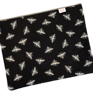 May include: Black fabric laptop sleeve with a white bee pattern.